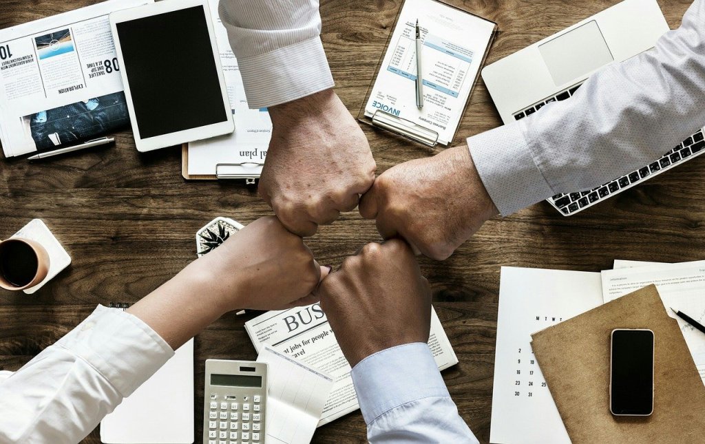 4 hands from diverse people working together in an office based business